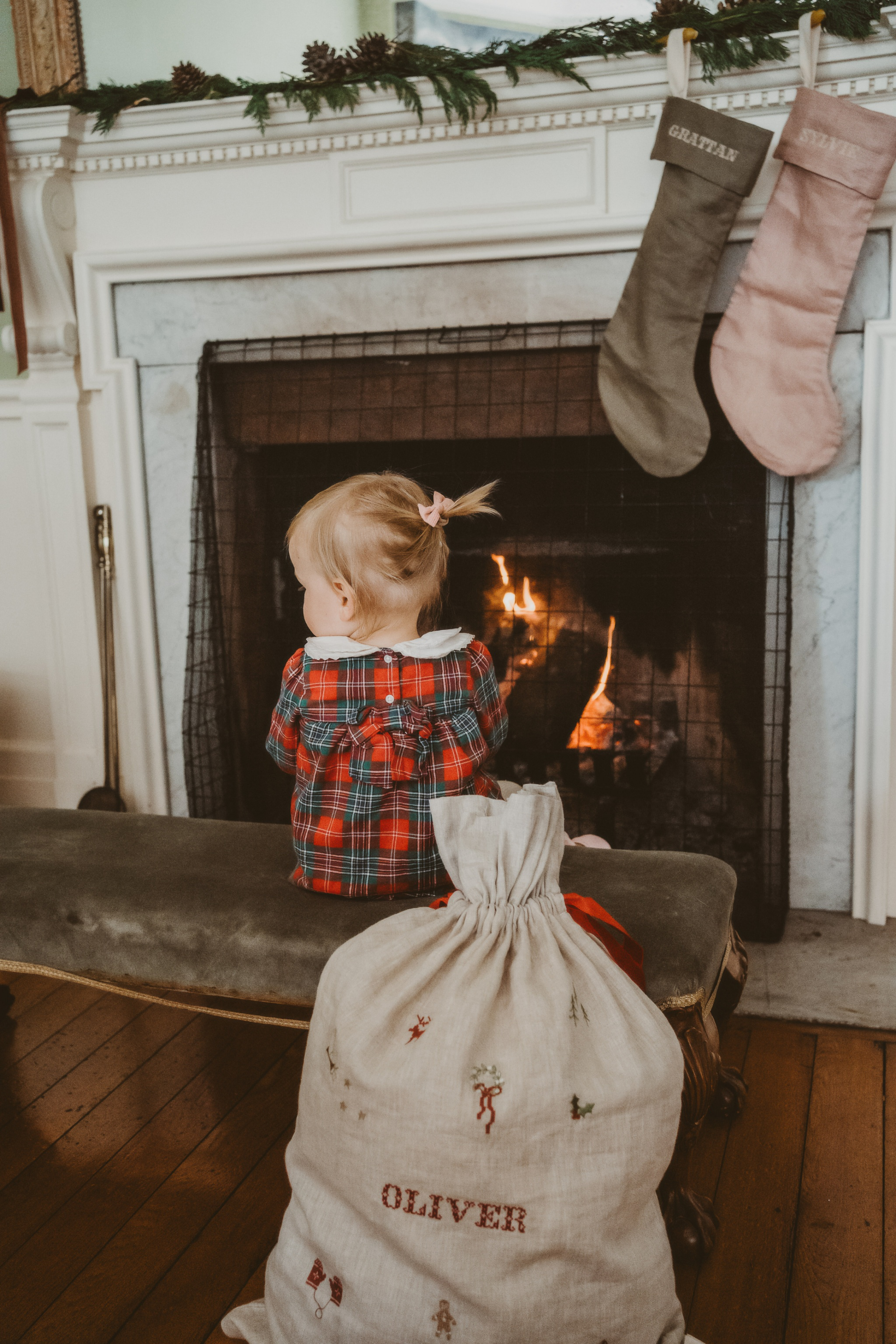 Personalized linen Santa sack with embroidered holiday motifs by fireplace
