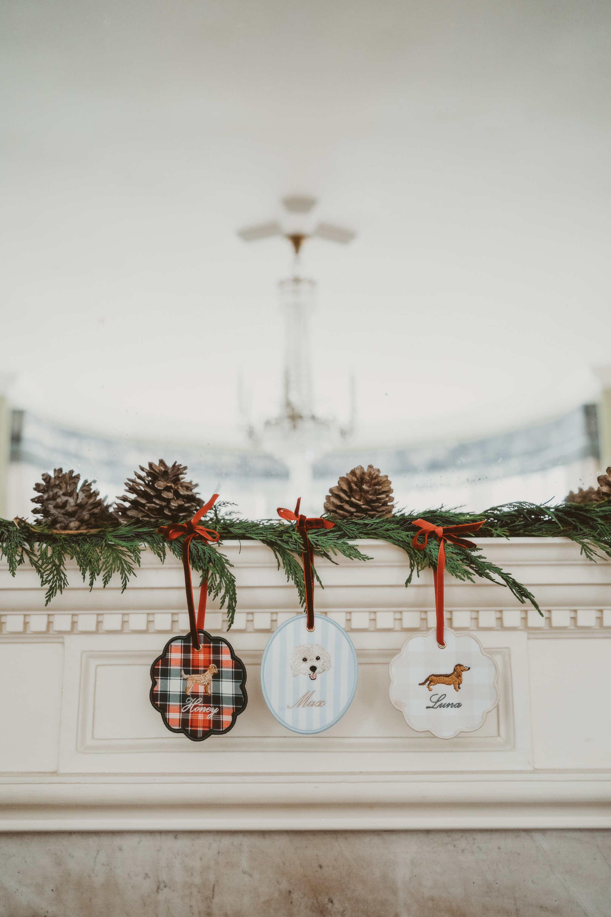 Personalised initials ornament set with festive designs hanging on garland above fireplace mantel