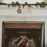 Personalised pet dog ornament hanging on mantelpiece with Christmas decorations above fireplace