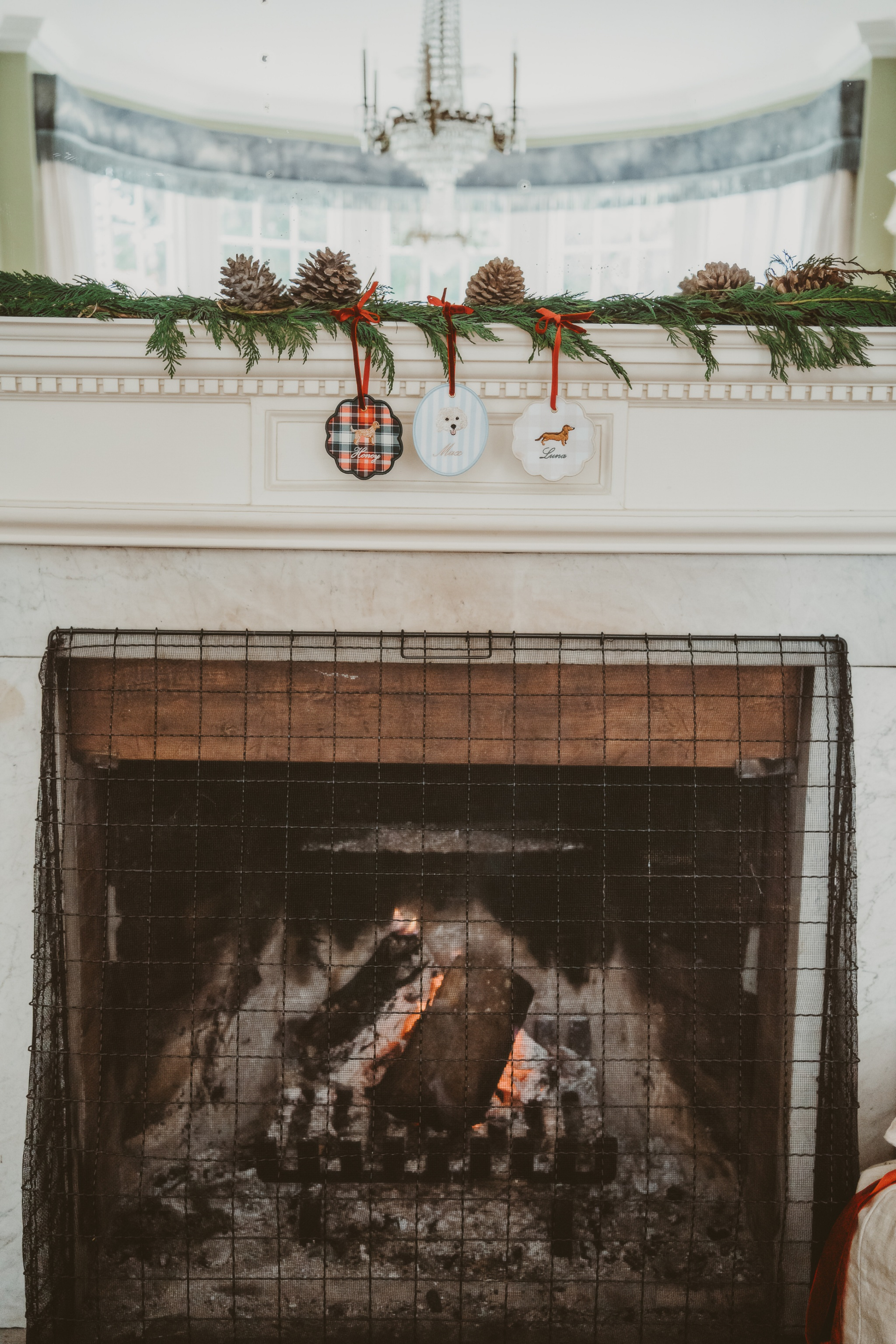 Personalised pet dog ornament hanging on mantelpiece with Christmas decorations above fireplace