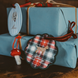 Personalised pet ornament with plaid design and dog silhouette charm attached to wrapped gift boxes