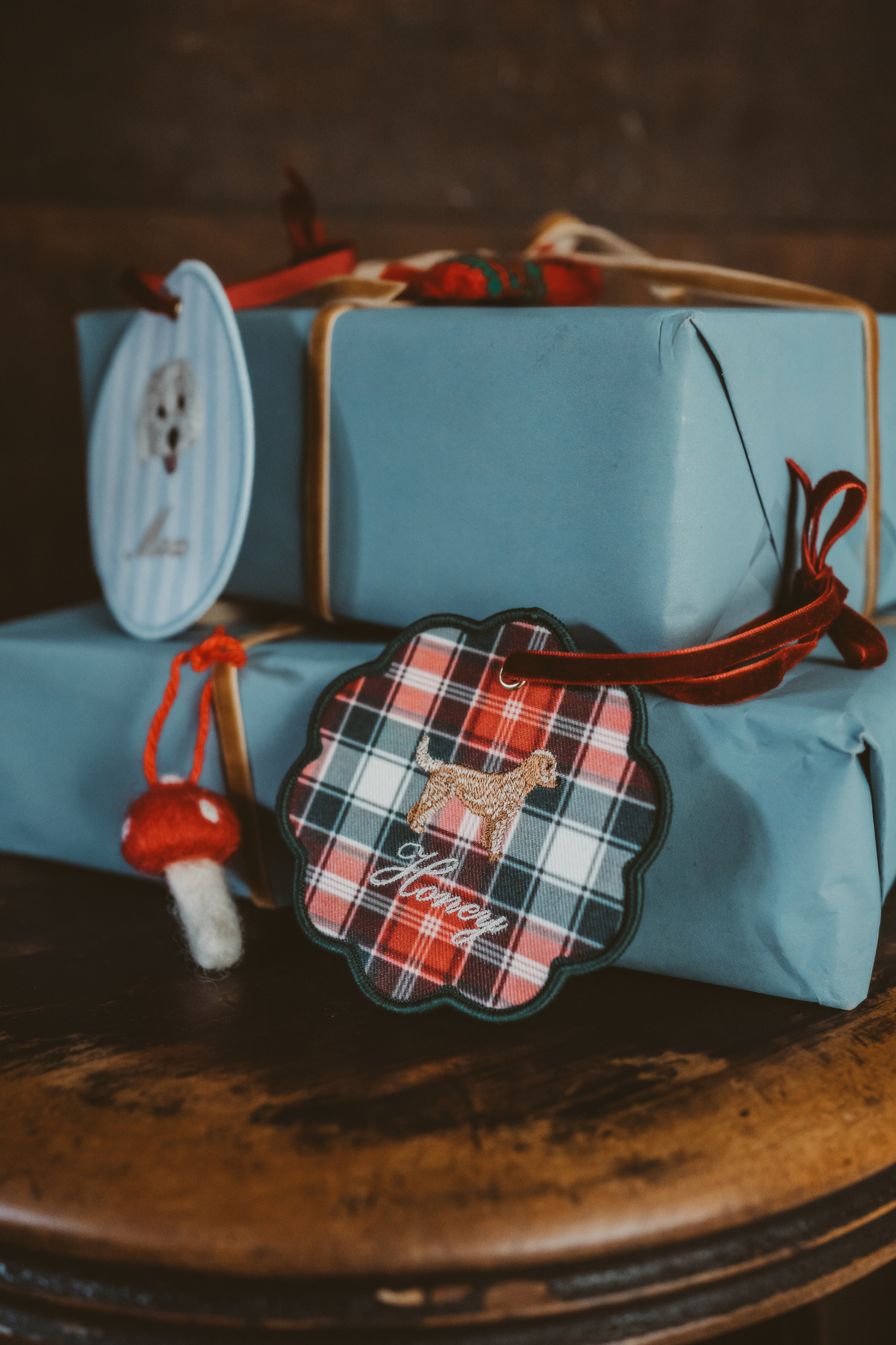 Personalised pet ornament with plaid design and dog silhouette charm attached to wrapped gift boxes