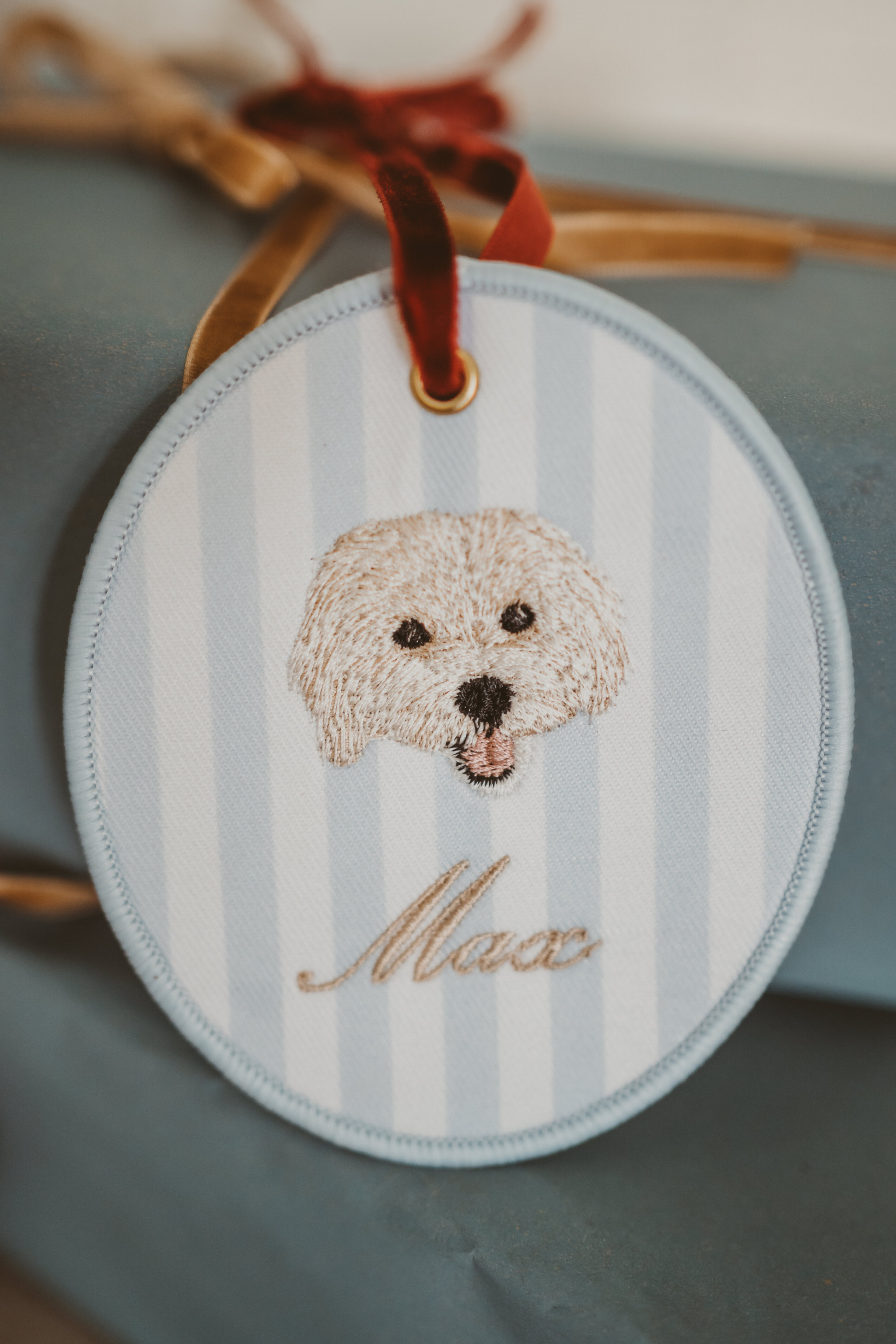 Personalised pet ornament with embroidered dog face and name Max on striped background, 10cm x 10cm.