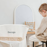 Personalised canvas chair bag with gingham pocket, embroidered with child's name, on small chair.