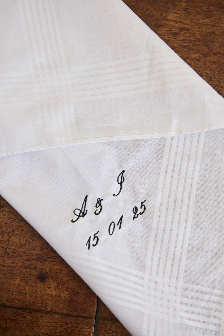 White cotton men's handkerchief with personalized embroidered initials and date on corner