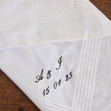 White cotton men's handkerchief with personalized embroidered initials and date on corner