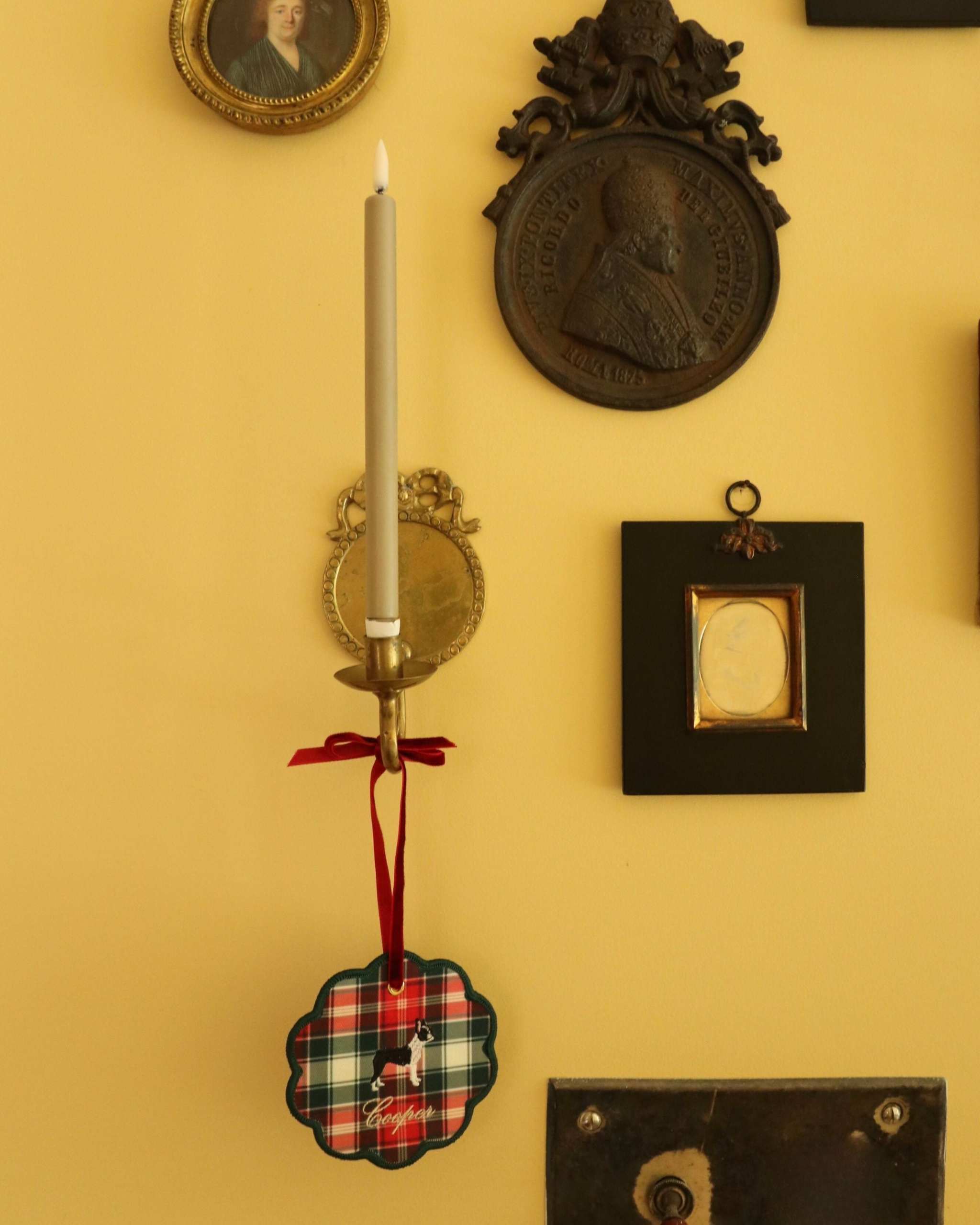 Custom embroidered pet ornament with plaid design and pet silhouette, personalized with pet name, hanging by a red ribbon