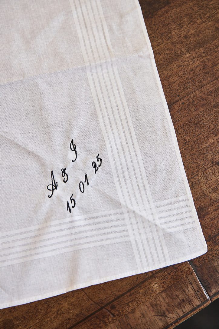 Personalized men's white cotton handkerchief embroidered with initials and date on wooden surface