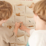 Children using personalized embroidered advent calendar with fabric pockets and red stitched names on cotton canvas