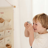 Child playing with personalized embroidered advent calendar hanging on wall with pockets and mini brass bells