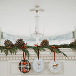 Personalised initials ornament set with festive designs hanging on garland above fireplace mantel