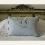 Duck egg blue linen cushion with embroidered vintage hot air balloons and personalized name on bed