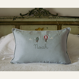 Duck egg blue linen cushion with embroidered vintage hot air balloons and personalized name on bed
