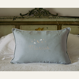 Blue Moon and Stars Cushion with embroidered name, featuring moon and stars needlework, white piping, and removable washable cover on bed