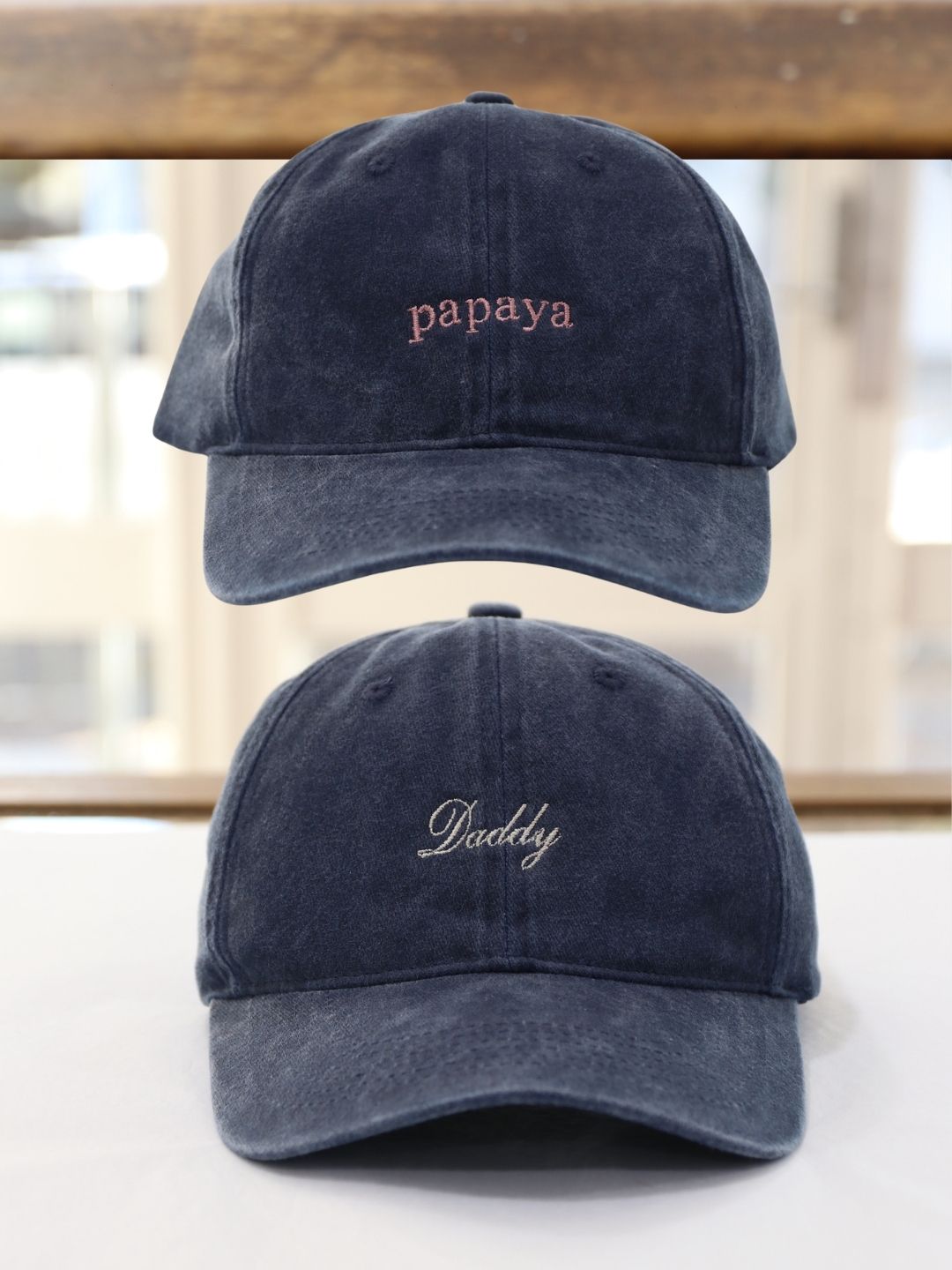 Two navy caps showing a short word and a family title in embroidered lettering