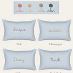 Botanical Linen Cushion with hand-embroidered names in pink, champagne, willow, and dark teal on light linen fabric.
