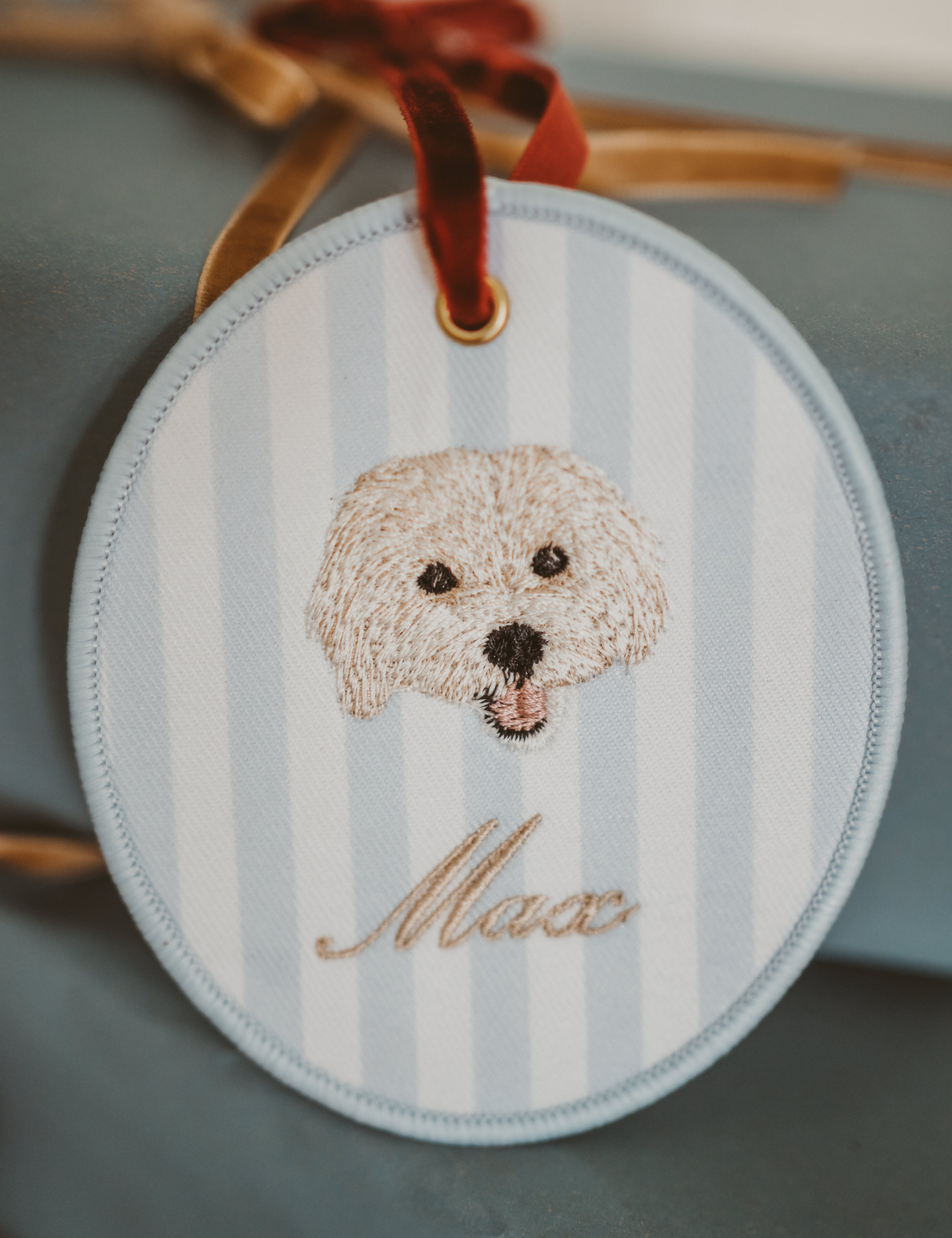 Personalised pet ornament with embroidered dog face and name Max on striped background, 10cm x 10cm.