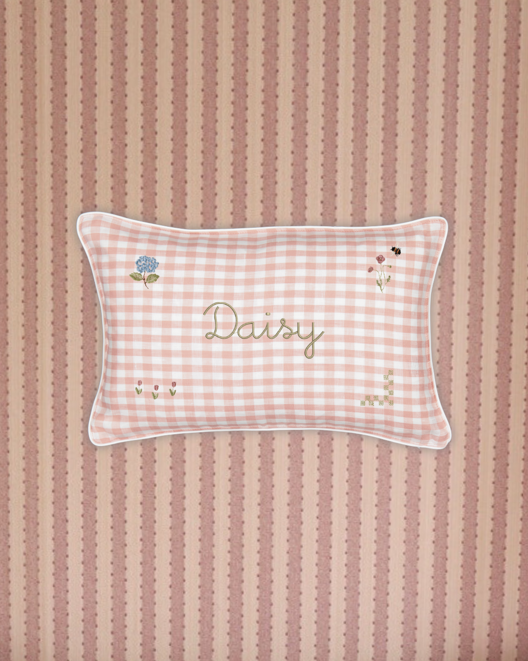 Botanical Linen Cushion with pink gingham pattern, floral embroidery, personalized name "Daisy," white piping, and soft removable cover.