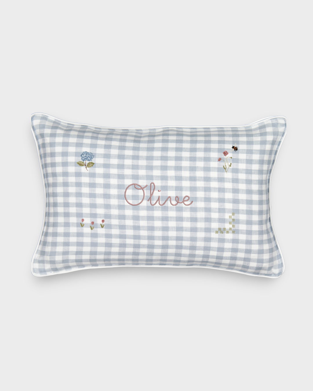 Botanical linen cushion with blue gingham pattern, hand-drawn floral embroidery, and personalized name "Olive" on front