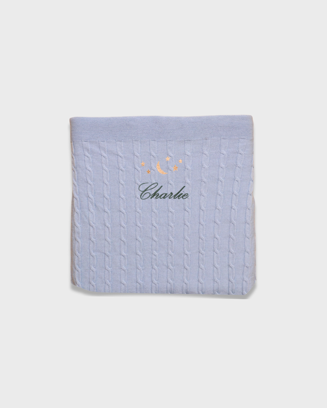 Soft blue Merino baby blanket with embroidered moon and stars design and personalized name Charlie.