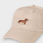 Beige personalised hat with hand-embroidered dachshund design on front and custom embroidery options on back, made of 100% washed cotton.