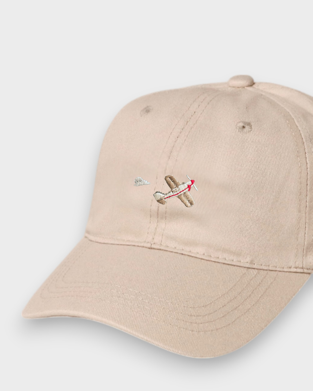 Beige 100% cotton baseball cap with embroidered airplane design, personalized text option, available in kids and adult sizes.