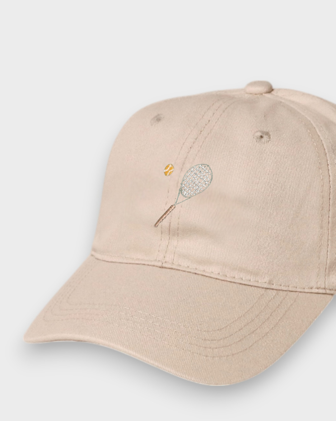 Beige personalised hat with embroidered tennis racket and ball design, made of 100% washed cotton in classic baseball style