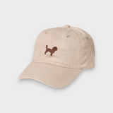 Beige Cavoodle personalised hat with hand-drawn embroidered Cavoodle design on front and custom embroidery on back in classic baseball style.
