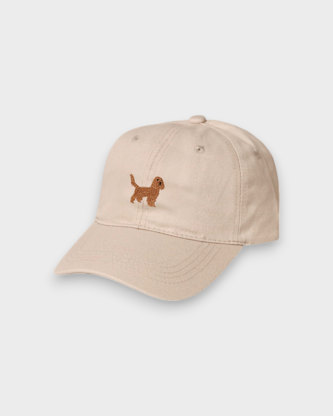 Beige baseball hat with embroidered brown Cocker Spaniel design on the front, made of 100% washed cotton, personalized embroidery option available.