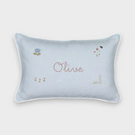 Botanical linen cushion with hand-drawn floral embroidery and personalized name "Olive" on light blue fabric with white piping.