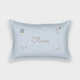 Botanical linen cushion with hand-drawn floral embroidery and personalized name "Olive" on light blue fabric with white piping.