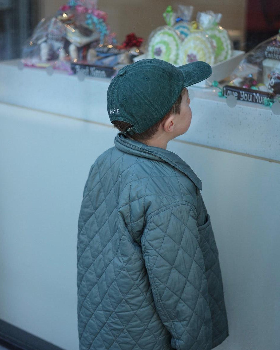Tennis personalised hat with embroidery design, worn by a child in a stylish quilted jacket.