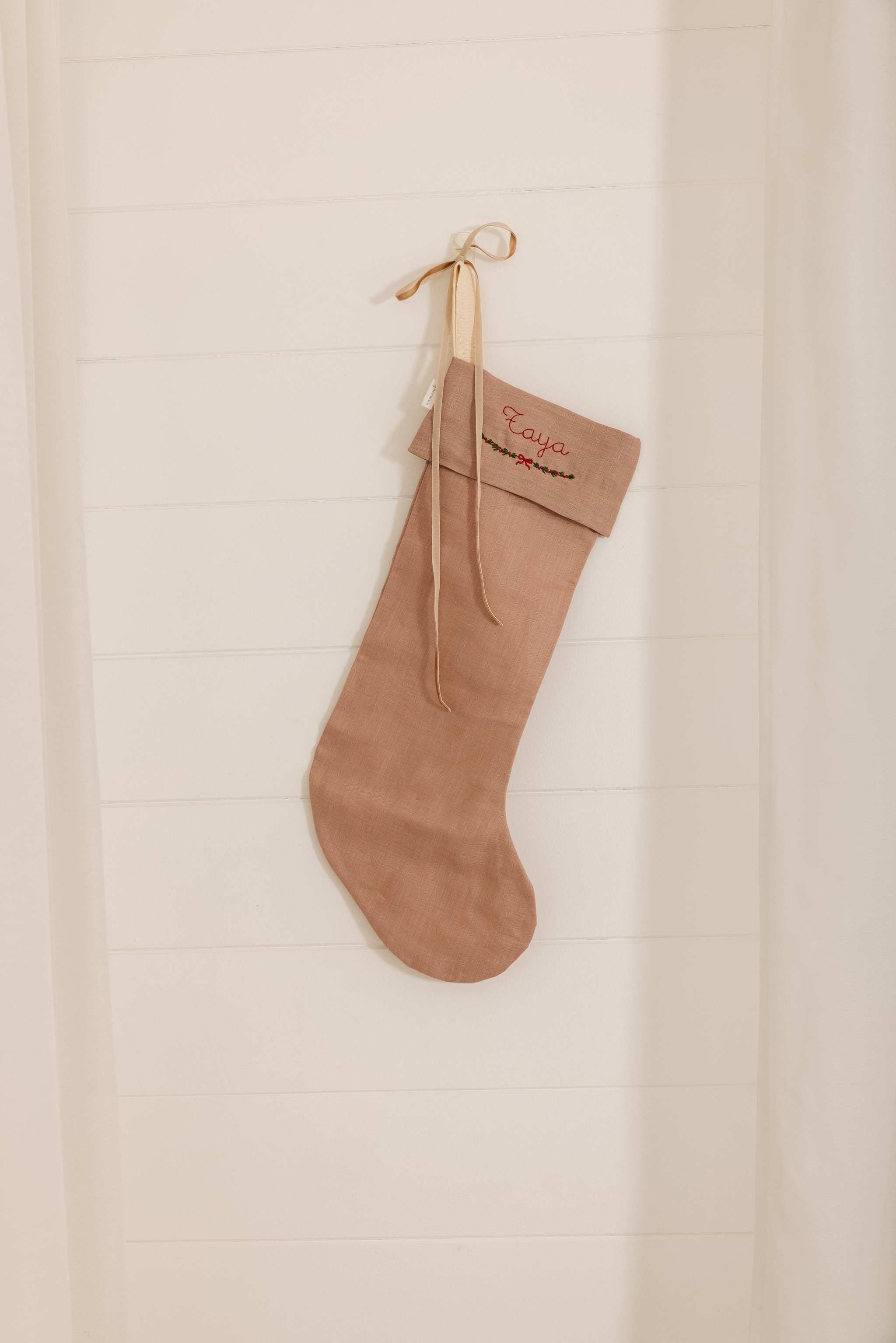 Personalised plain linen stocking with Nordic Cross Stitch name embroidery hanging on wall