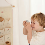Child playing with personalized embroidered advent calendar hanging on wall with pockets and mini brass bells