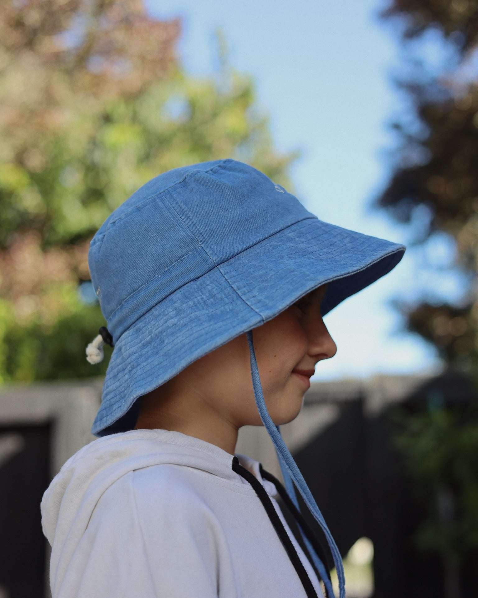 Customised blue bucket hat on a child made of 100% washed cotton, individually embroidered in Auckland.